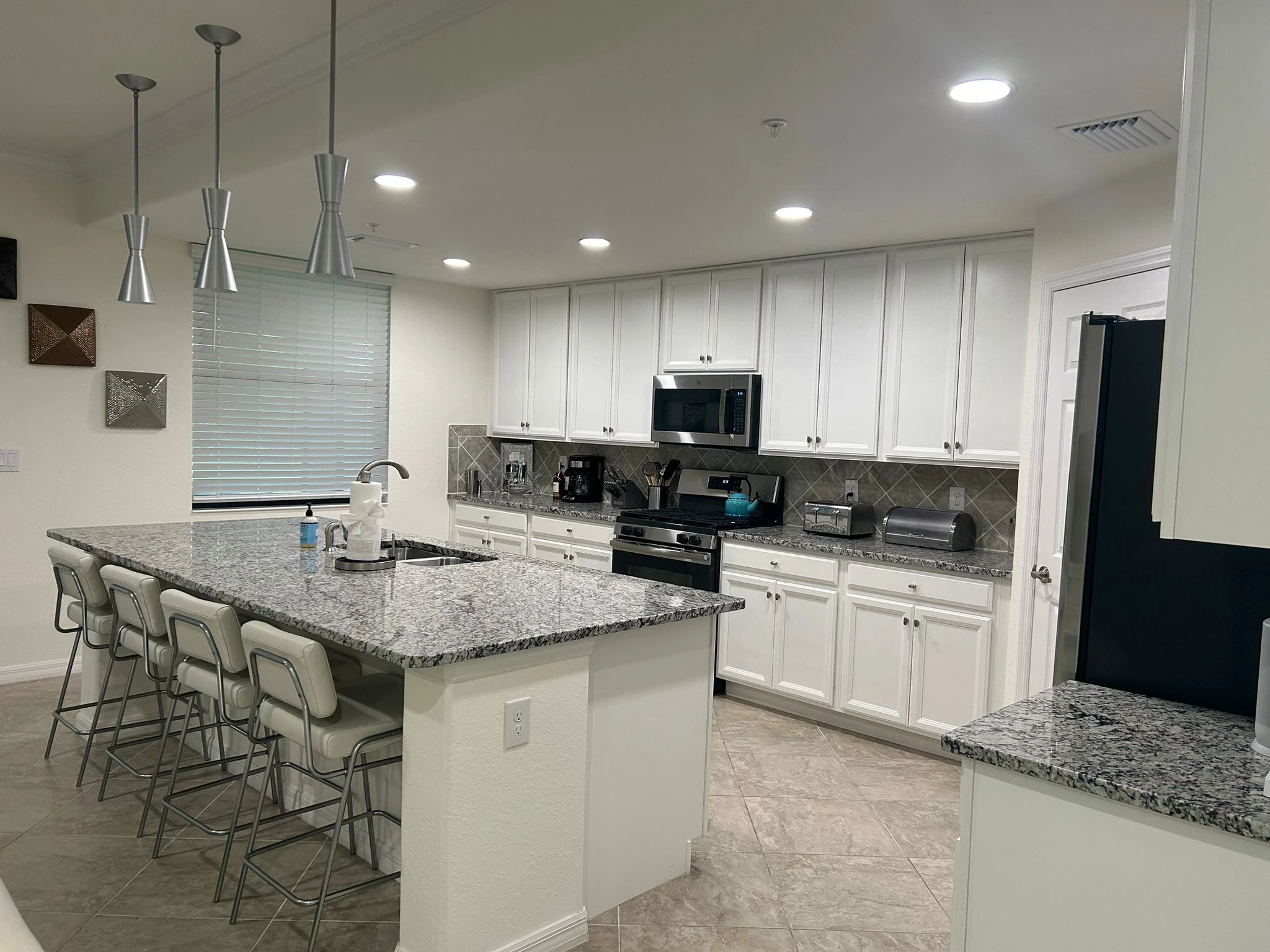 Clean white kitchen with a granite island