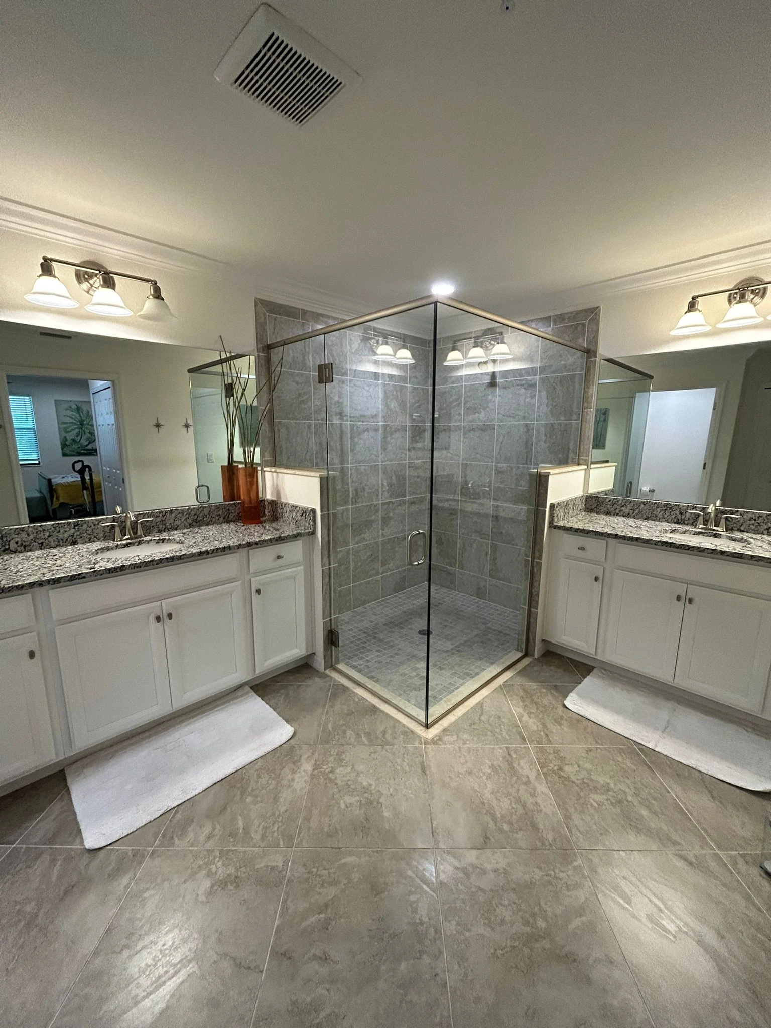 Clean bathroom with glass shower and white vanities
